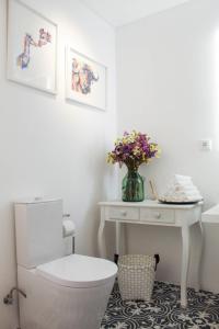 a bathroom with a toilet and a table with flowers at Casa da Tasquinha in Ponta Delgada +35 photos