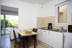 a kitchen with a table with a bowl of fruit on it at Motel le Vieux Moulin in LʼÎle-Rousse