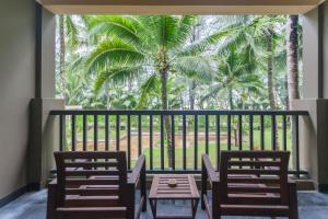 un balcón con mesa, sillas y una palmera en Grand Southsea Khaolak Beach Resort, en Khao Lak
