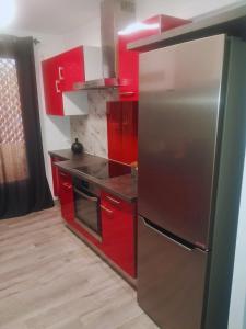 a kitchen with red cabinets and a stainless steel refrigerator at Bel appartement T3 avec parking in Avignon