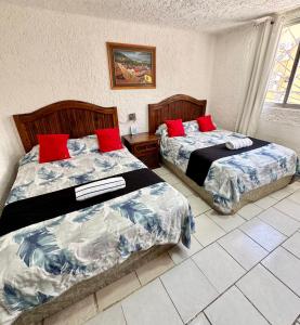 two beds in a hotel room with red pillows at Hotel Farallon Inn Cancún in Cancún