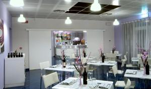 a restaurant with white tables and chairs and a bar at Aurea Hotel in Tortoreto Lido