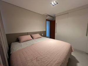 a bedroom with a bed with two pink pillows at Apê Confortável com ar condicionado in Lucas do Rio Verde