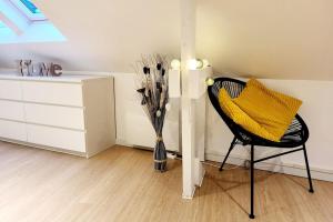 a room with a chair and a dresser and a vase with sticks at Le Petit Langlet - Cathedral - hyper-center in Reims