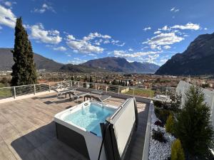 a hot tub on a deck with mountains in the background at Attico Sky Lake Holiday Luxury Apartament in Riva del Garda