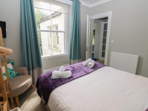 a bedroom with a bed and a chair and a window at Hampton House in St Bees