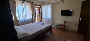 a small bedroom with a bed and a television at Zamia Heights Apartments in Gatunga