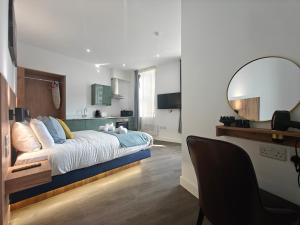 a bedroom with a bed with a mirror and a chair at 10 Chic studio Apartments in Birmingham city centre in Birmingham