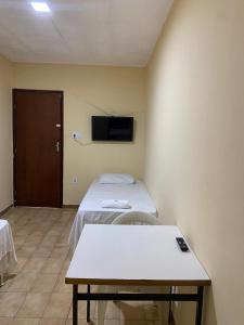 a room with a bed and a table and a tv at Hotel Vale Das Serras in Jacobina