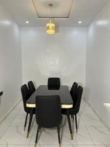une salle à manger avec une table noire et des chaises noires dans l'établissement Orchard Apartments Ile - Ife Osun State Nigeria, à Ile-Ife