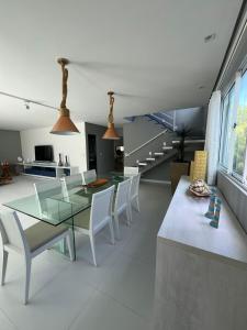 ein Esszimmer mit einem Glastisch und weißen Stühlen in der Unterkunft Casa Toquinho Ipojuca-PE in Ipojuca