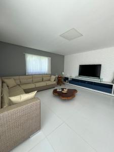 ein Wohnzimmer mit Couch und Flachbildfernseher in der Unterkunft Casa Toquinho Ipojuca-PE in Ipojuca