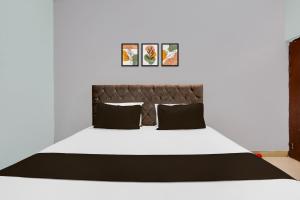 a bedroom with a white bed with black pillows at Hotel O HERITAGE HOTEL in Hardoī