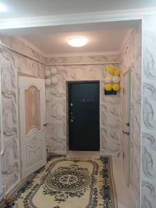 a hallway with a black door and a rug at Bakvt Homestay & Breakfast & Horse Riding Tours in Dzhangyaryk