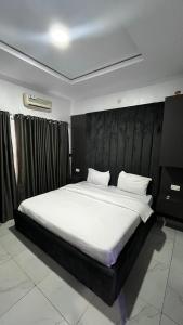une chambre avec un grand lit avec des draps blancs dans l'établissement Orchard Apartments Ile - Ife Osun State Nigeria, à Ile-Ife