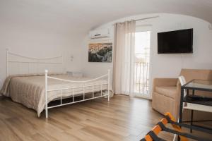 a bedroom with a bed and a couch and a tv at Le Segrete in Gravina in Puglia