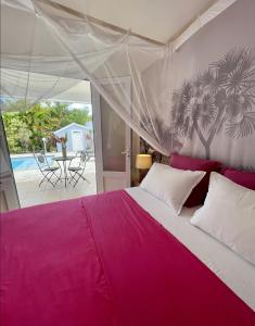 a bedroom with a large bed with pink sheets at Villa Amaryllis in Le Gosier