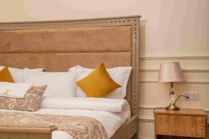 Fort PortalにあるPekasa Palace Hotelのベッドルーム1室(白い枕とランプ付きのベッド1台付)