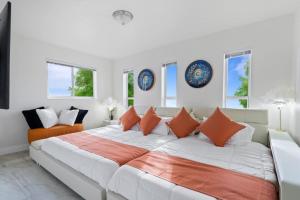 a white bedroom with a large bed with orange pillows at 4BR Hollywood Villa 3 min to Beach, Heated 12-Person Jacuzzi, Game Room and BBQ in Hollywood
