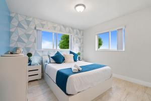a bedroom with a large bed and two windows at 4BR Hollywood Villa 3 min to Beach, Heated 12-Person Jacuzzi, Game Room and BBQ in Hollywood