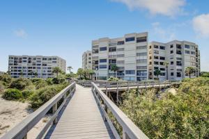 a boardwalk over the beach with buildings in the background at Amelia Surf and Racquet Club Condo - 1st Floor Ocean View - Pools - Tennis Courts - Sleeps 4 in Fernandina Beach