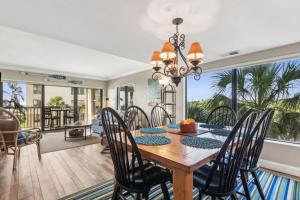 a dining room with a table and chairs and a large window at Amelia Surf and Racquet Club Condo - 3rd Floor - Ocean View - Pools - Tennis Courts - Sleeps 8 in Fernandina Beach