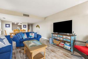 a living room with a blue couch and a flat screen tv at Amelia Surf and Racquet Club Condo - Ocean View - 1st Floor - Pools - Tennis Courts - Sleeps 8 in Fernandina Beach