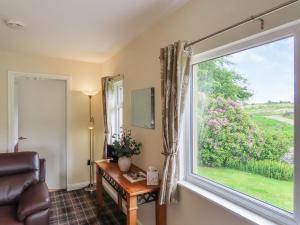 a living room with a window and a table and a chair at Swallow Lodge in Carsphairn