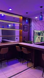 - un bar avec des chaises et une télévision dans la chambre dans l'établissement Orchard Apartments Ile - Ife Osun State Nigeria, à Ile-Ife