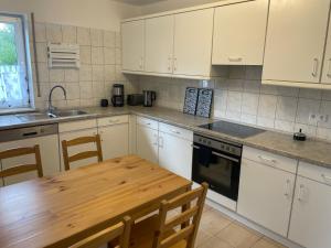 a kitchen with white cabinets and a wooden table at Eastside - Apartment WHG 02 in Senftenberg