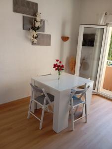 a white table with two chairs and a vase with flowers on it at Résidence la Citadelle in Saint-Florent