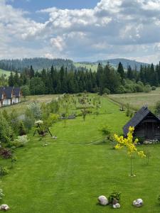 a field of grass with a house and trees at Framptons Apartments Garden & Spa - Dla dorosłych i dzieci 12 plus - Adults and children 12 plus in Murzasichle