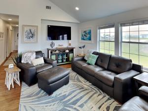 a living room with a leather couch and chairs at Inn at Dolphin Bay in Rockport