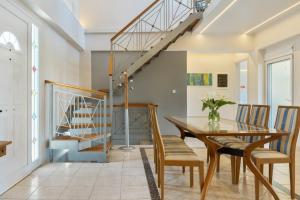 een eetkamer met een tafel en stoelen en een trap bij Beach Family Villa in Artemida in Artemida