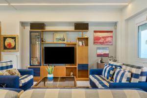 een woonkamer met blauwe banken en een flatscreen-tv bij Beach Family Villa in Artemida in Artemida
