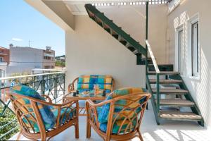 een balkon met twee stoelen en een tafel en een trap bij Beach Family Villa in Artemida in Artemida