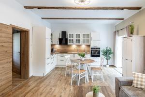 a kitchen with white cabinets and a table and chairs at Ferienbahnhof Fichtental Stellwerk Suite in Prackenbach