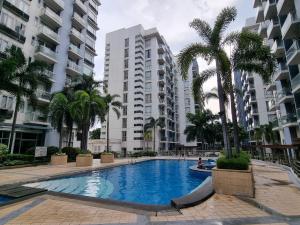 a large swimming pool with palm trees and buildings at Palm Tree Condos across NAIA3 by Beth in Manila