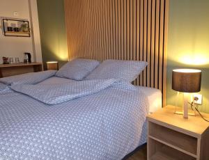 Schlafzimmer mit einem Bett mit blauer Bettwäsche und einer Lampe in der Unterkunft Apartmani i sobe PARK in Apatin