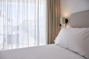 a bedroom with a white bed and a large window at Sercotel Cruz Del Mar in Chipiona