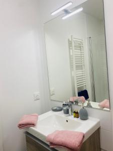 a bathroom with a sink with a mirror and pink towels at chambre avec salle de bain privée au cœur de La Défense in Nanterre +12 photos