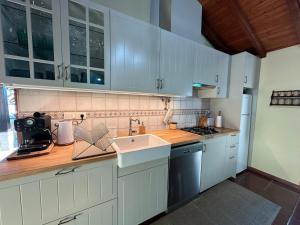 a kitchen with white cabinets and a sink at Casa da Forja - Gerês in Gondoriz