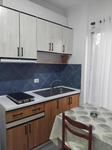 a kitchen with white cabinets and a sink and a table at Vila Rei in Borsh