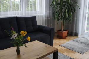 a living room with a couch and a table with flowers at Apartament Tarnów-Mościce PRZY MOŚCIE in Tarnów +9 photos