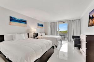 Habitación blanca con 2 camas y balcón. en Ocean Manor Beach Resort, en Fort Lauderdale