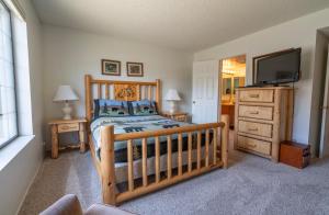 a bedroom with a crib and a flat screen tv at Rr-interlaken 25 in June Lake