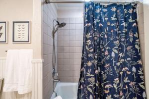 Un baño con ducha con cortina de ducha floral azul. en Country House New Pool, Five mins to Town, en Fredericksburg 31 fotos más