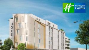 un gran edificio blanco con una señal verde al lado en Holiday Inn Express Paris - Poissy by IHG, en Poissy