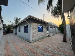 a small building on a brick road next to a building at Cozy Stay Near Zanzibar Airport in Zanzibar City