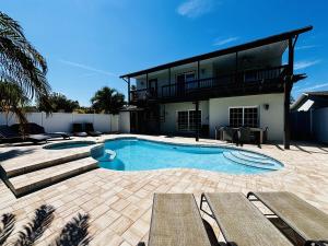 a swimming pool with two benches and a house at 4 Bedroom home with heated pool by the beach! in Clearwater Beach